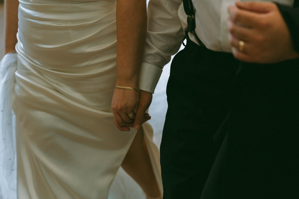 Close up of bride and groom walking holding hands, by Elsie Goodman Photography.