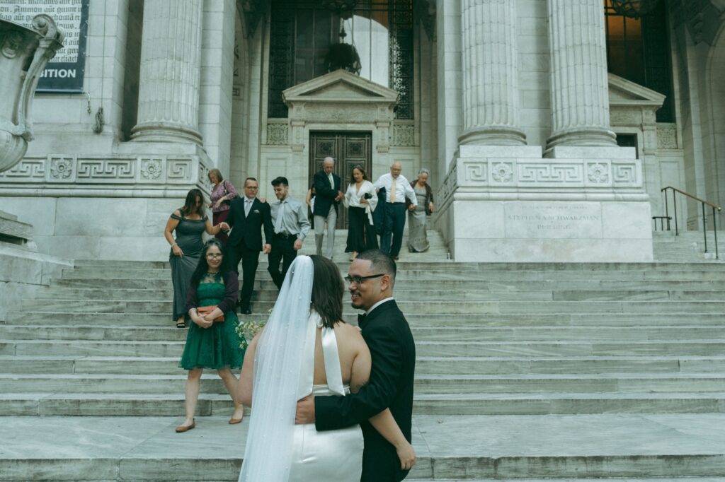 Wedding guests descend the steps of the New York Public Library after the NYPL elopement ceremony, by Elsie Goodman.