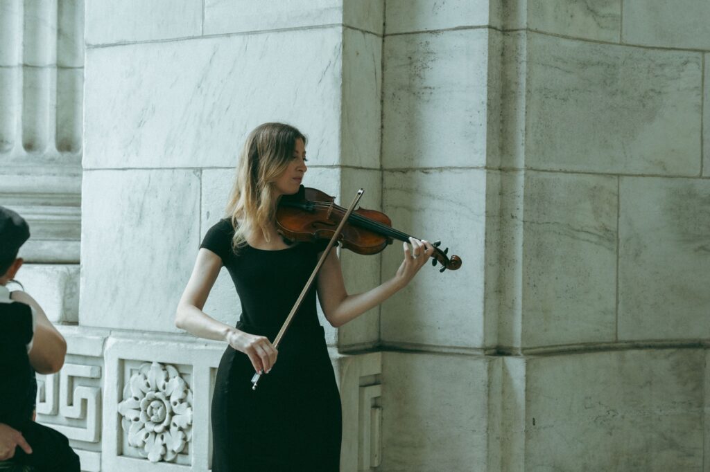 Violinist performs near marble columns during a New York Public Library wedding ceremony, by Elsie Goodman.