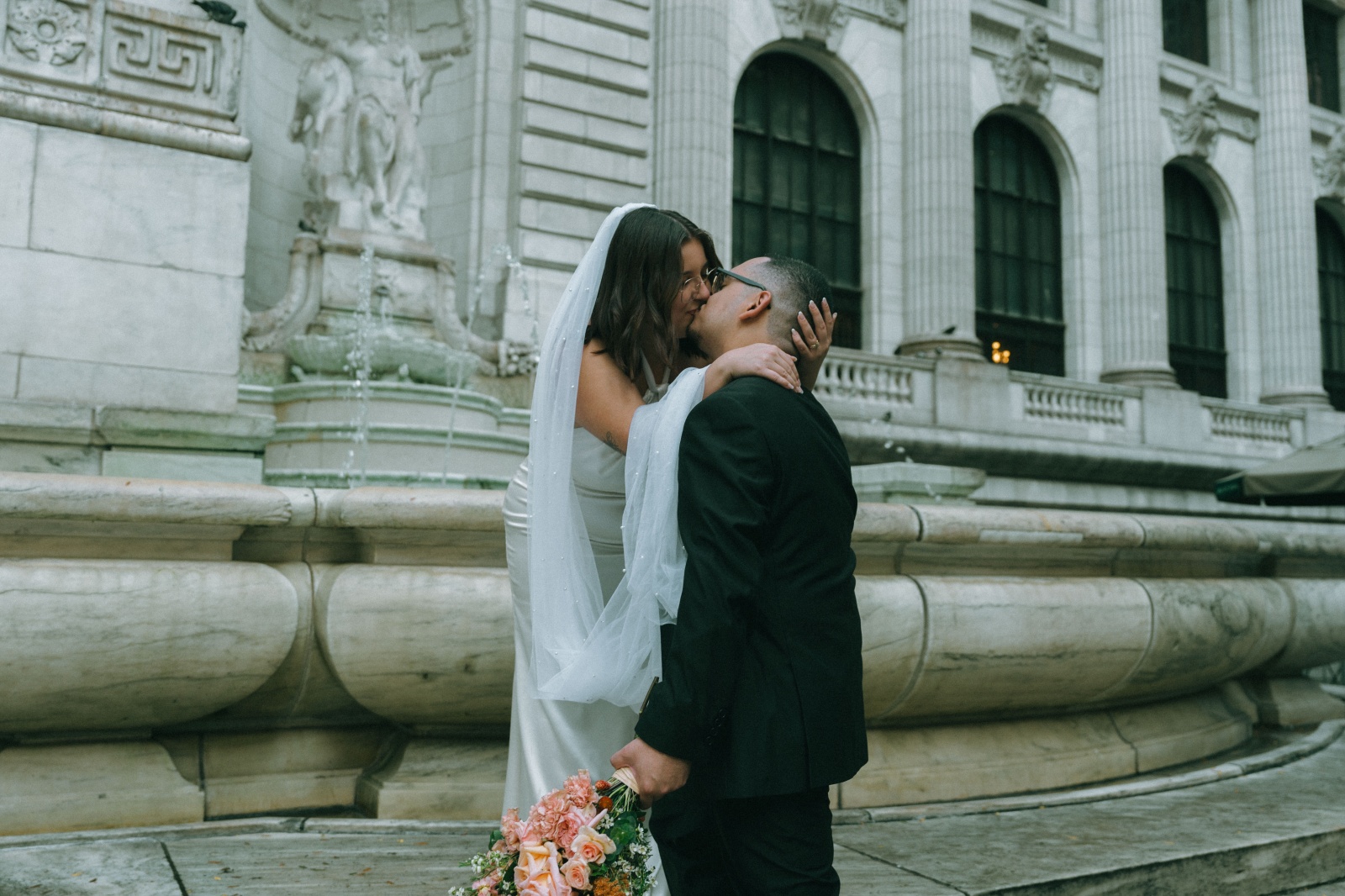 Bride and groom share kiss by NYPL fountain after elopement, photographed by Elsie Goodman.