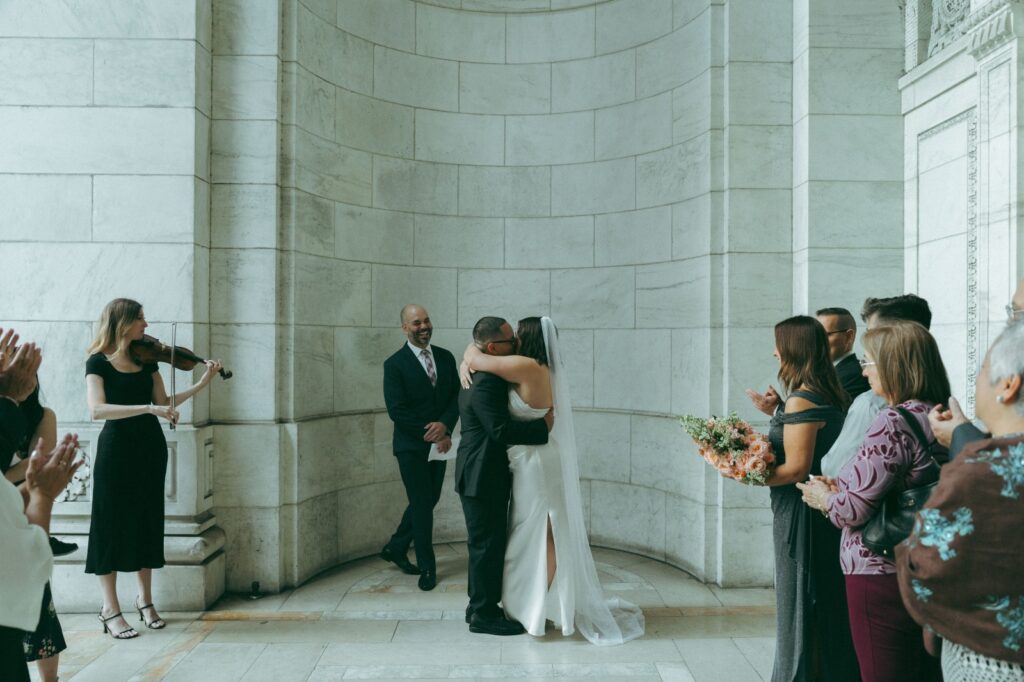 Groom and bride share first kiss during NYPL wedding ceremony, photographed by Elsie Goodman.