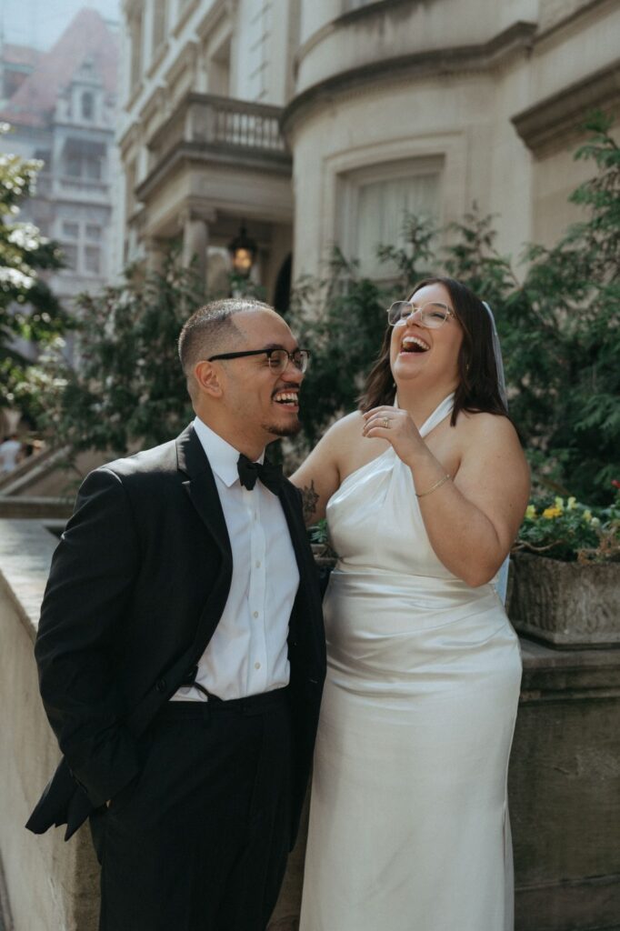 Bride and groom share laughter on sidewalk after NYPL wedding, photographed by Elsie Goodman.