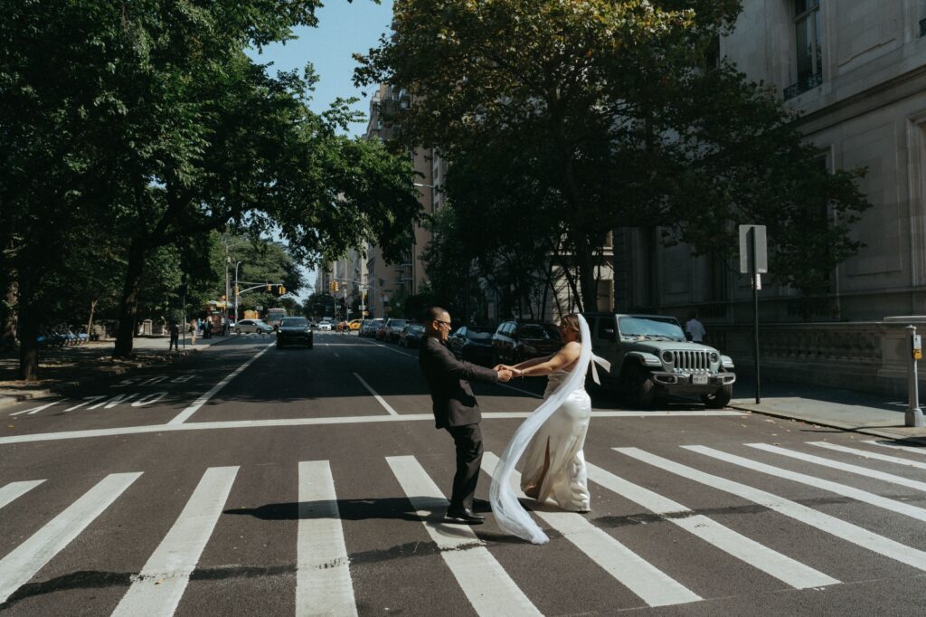 Bride and groom twirl in crosswalk after New York Public Library wedding, captured by Elsie Goodman.