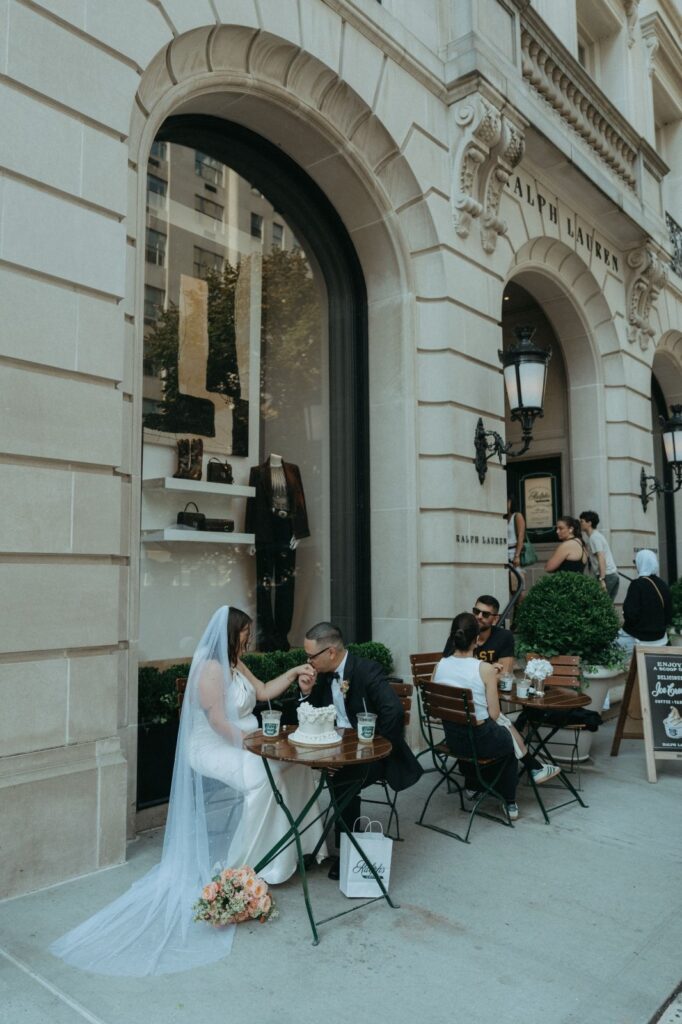 Groom kisses bride's hand outside of Ralph's after their NYC elopement, shot by Elsie Goodman.