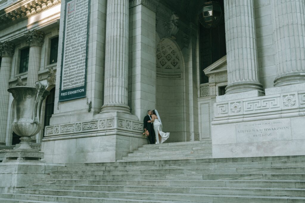 Bride and groom share a kiss on top of the NYPL steps after eloping, captured by Elsie Goodman.