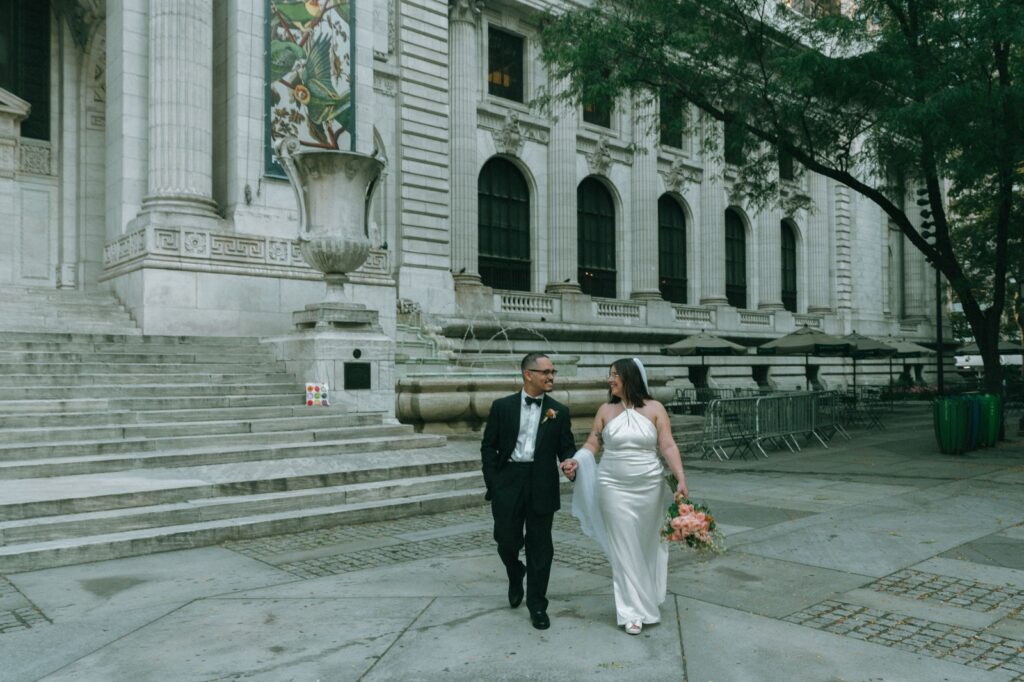 Bride and groom walk hand in hand outside of NYPL after eloping, shot by Elsie Goodman.