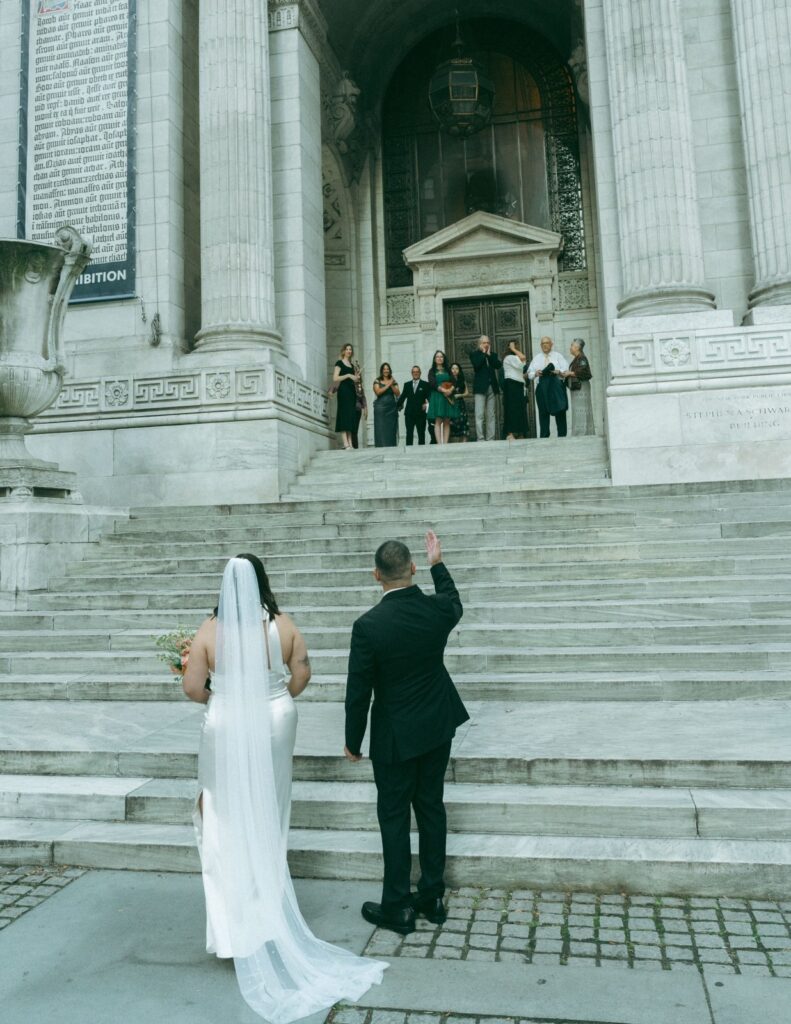 Bride and groom call to guests from bottom of NYPL steps after eloping, shot by Elsie Goodman.