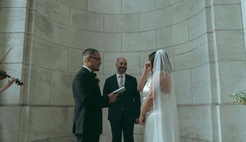 Bride wipes away tears during vows at New York Public Library wedding, by Elsie Goodman Photography.