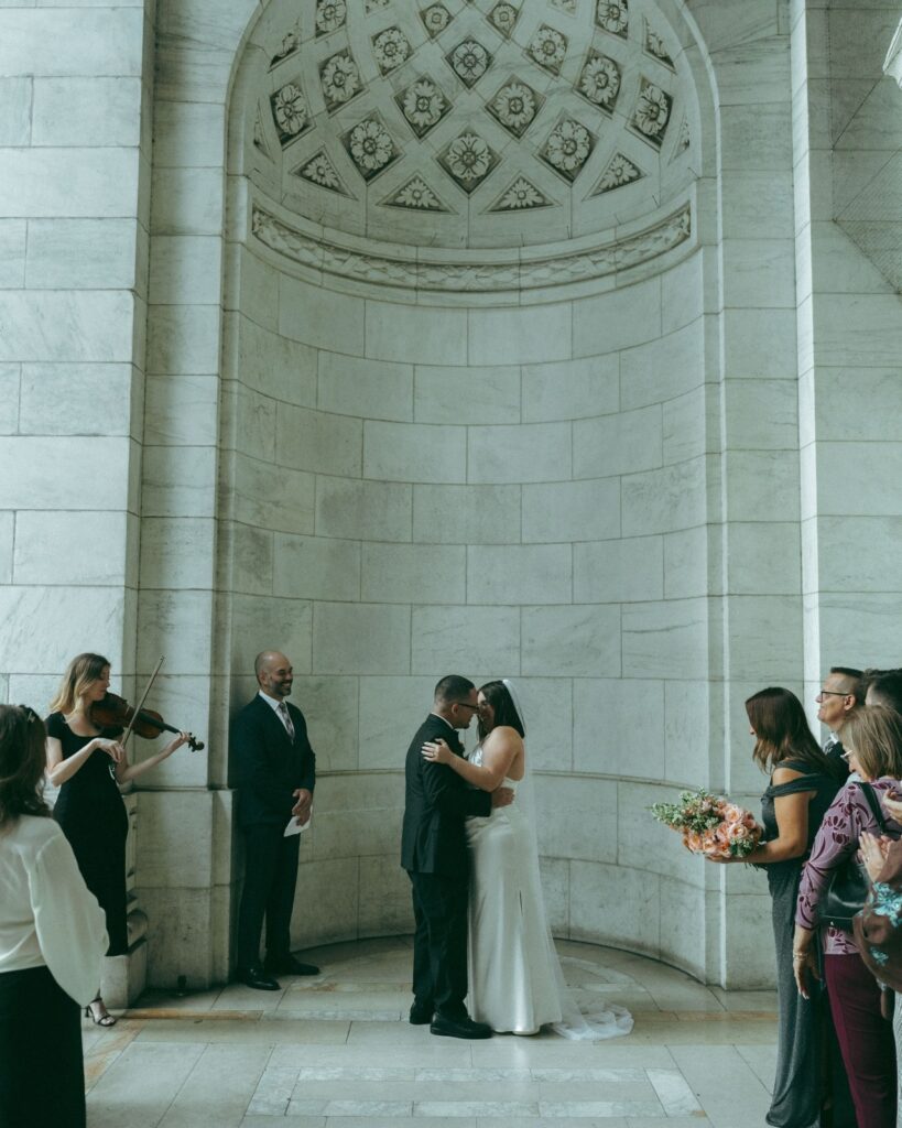 Bride and groom smile at each other after their first kiss at an New York Public Library elopement, by Elsie Goodman.