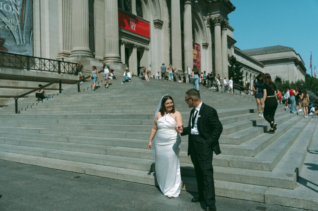 Bride and groom hold hands in front of MET steps after eloping, by Elsie Goodman.