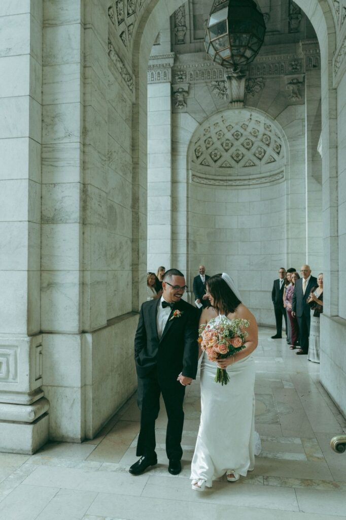 Bride and groom look at each other while walking down aisle after eloping, shot by Elsie Goodman.