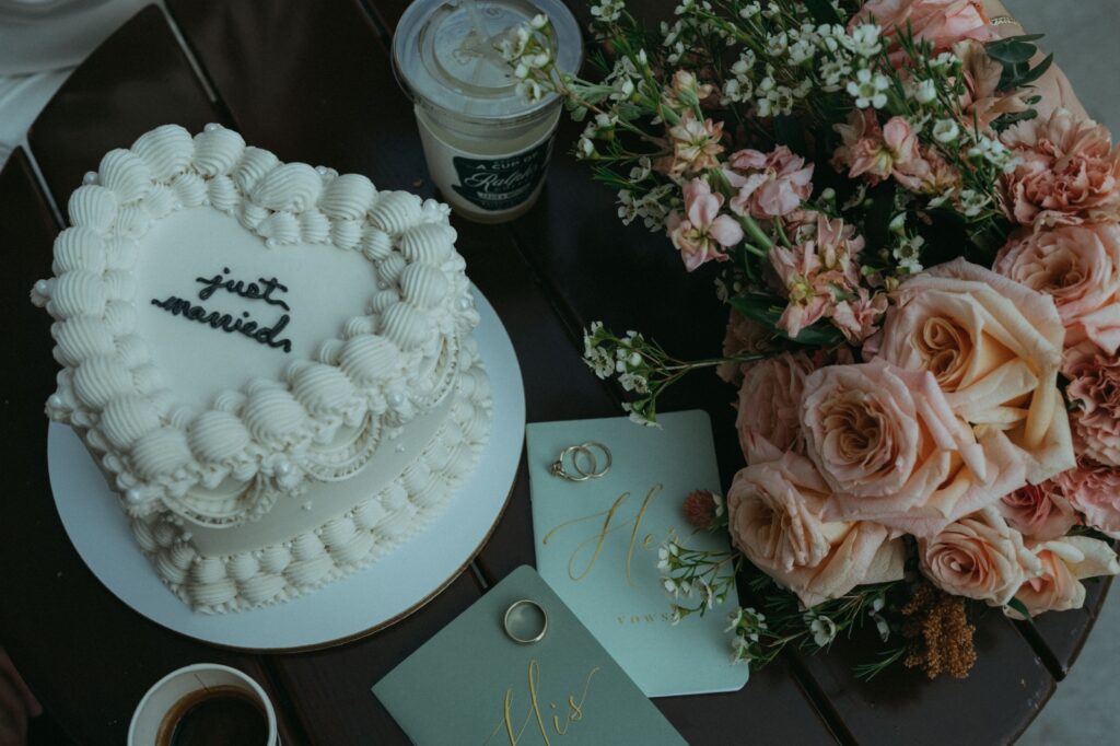 Details shot of wedding cake, bouquet, vow books, rings, and coffee for an NYPL elopement, by Elsie Goodman.