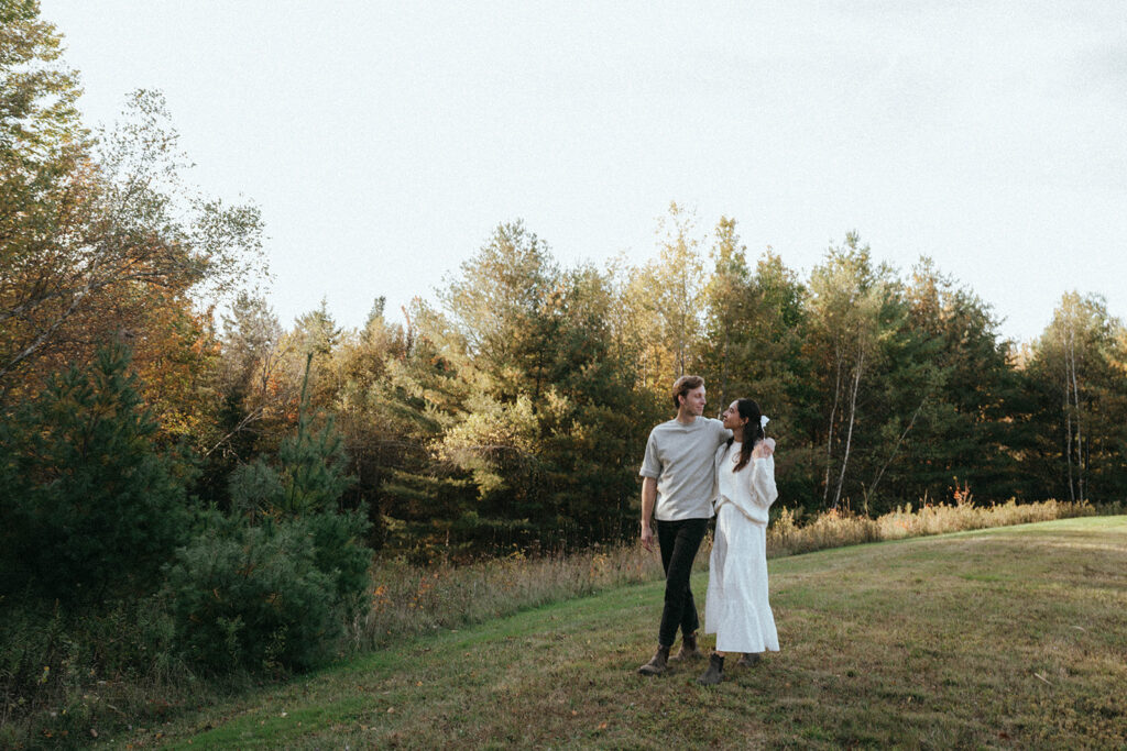 Fall in Vermont couple walking in forest clearing, by Elsie Goodman Photography.
