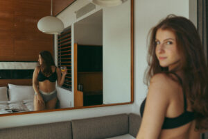 hotel boudoir photography with woman in mirror holding drink, shot by Elsie Goodman Photography.