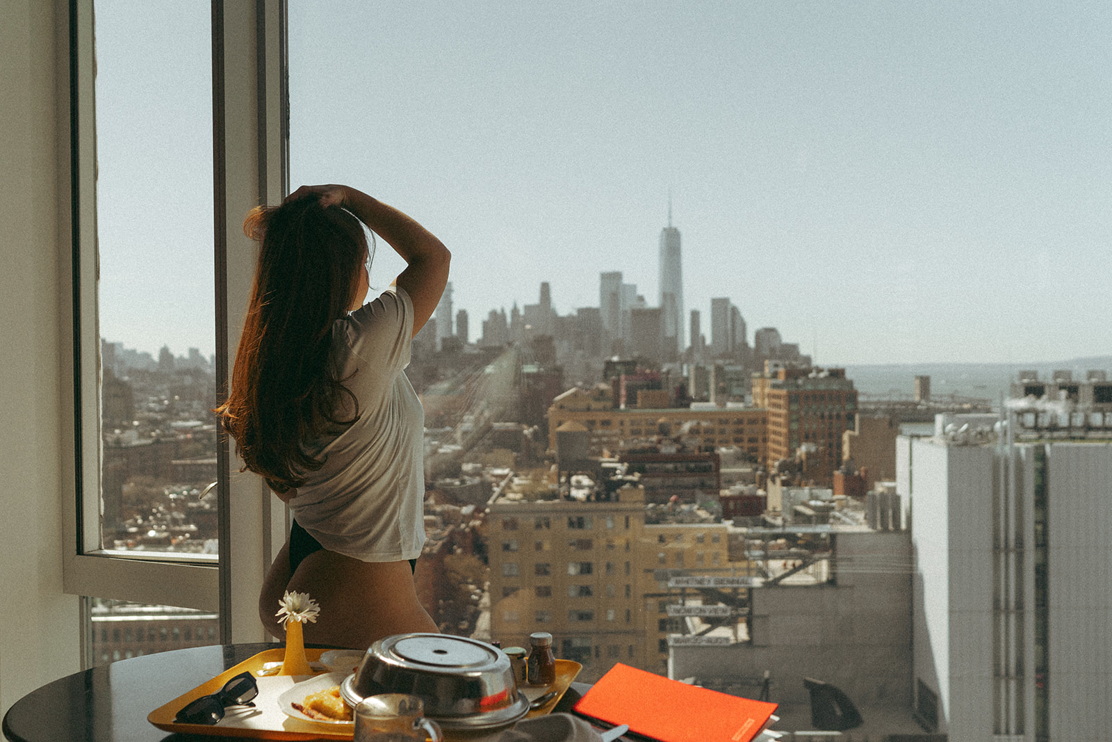 hotel boudoir photo of woman looking out window over New York skyline, shot by Elsie Goodman Photography.