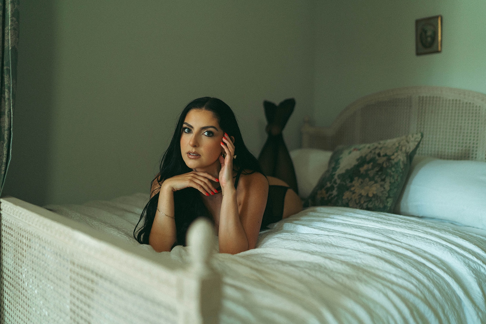 Intimate boudoir photoshoot at home with woman lying on bed in black lingerie, feet playfully against the headboard, shot by Elsie Goodman Photography.