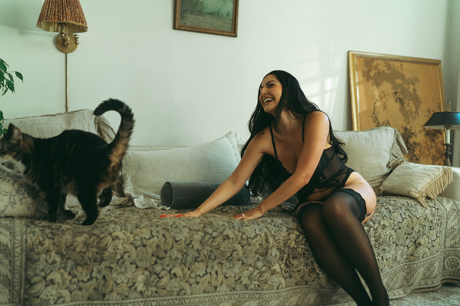 Playful boudoir photoshoot at home with cat walking across bed during intimate lifestyle session, shot by Elsie Goodman Photography.