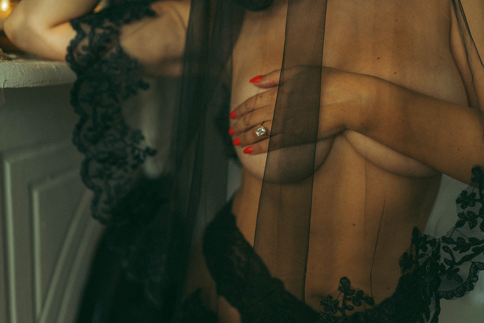 Bridal boudoir photoshoot at home featuring close-up of lace veil and red nails over bare chest, shot by Elsie Goodman Photography.