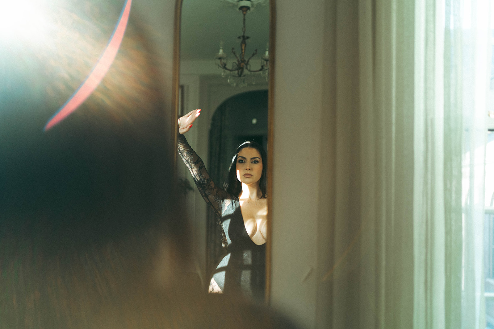 Artistic boudoir photoshoot at home showing a woman’s reflection in the mirror with soft sunlight adding a dreamy effect, shot by Elsie Goodman Photography.