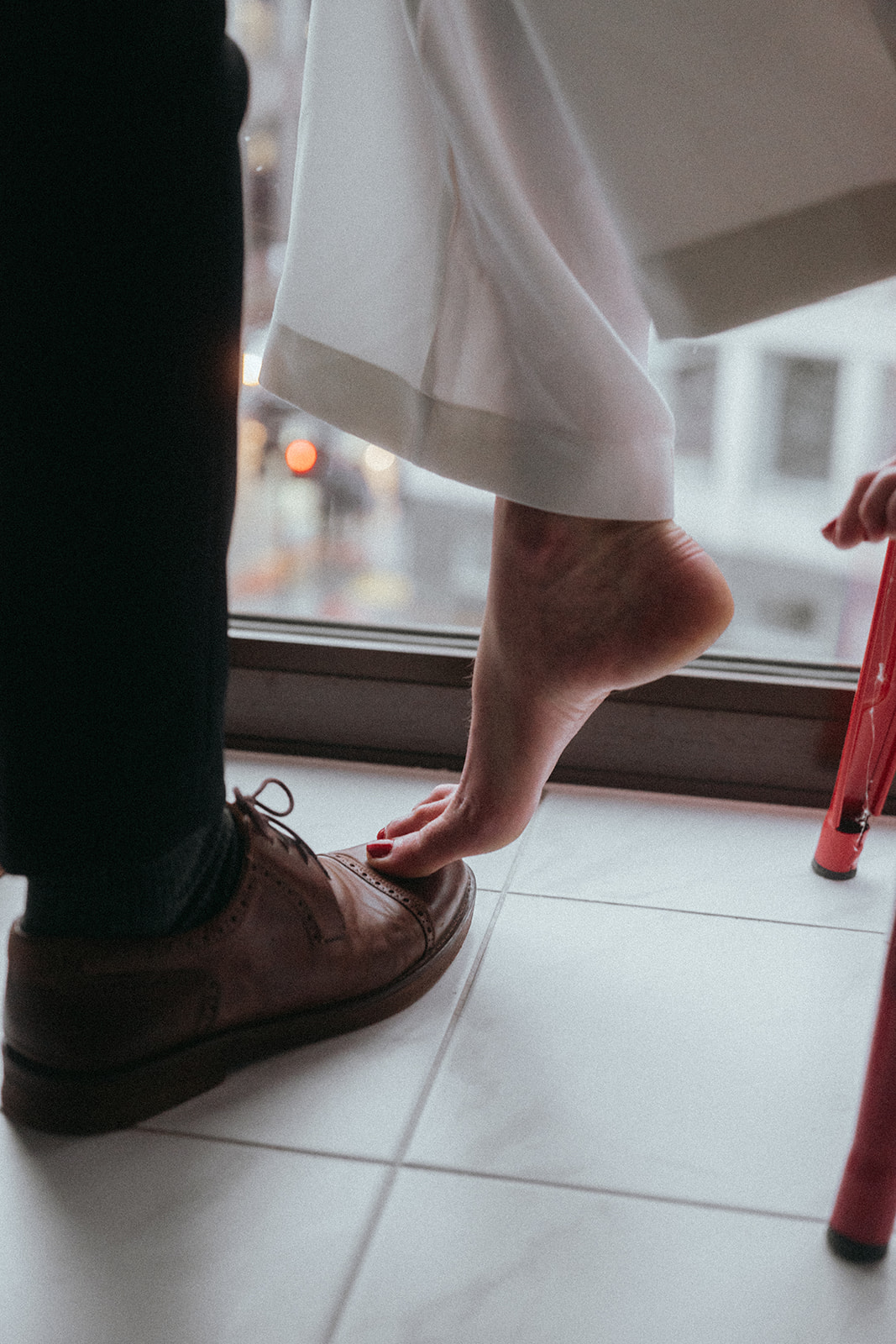 A woman's bare foot perched on top of a man's dress shoe, shot by London engagement photographer Elsie Goodman.