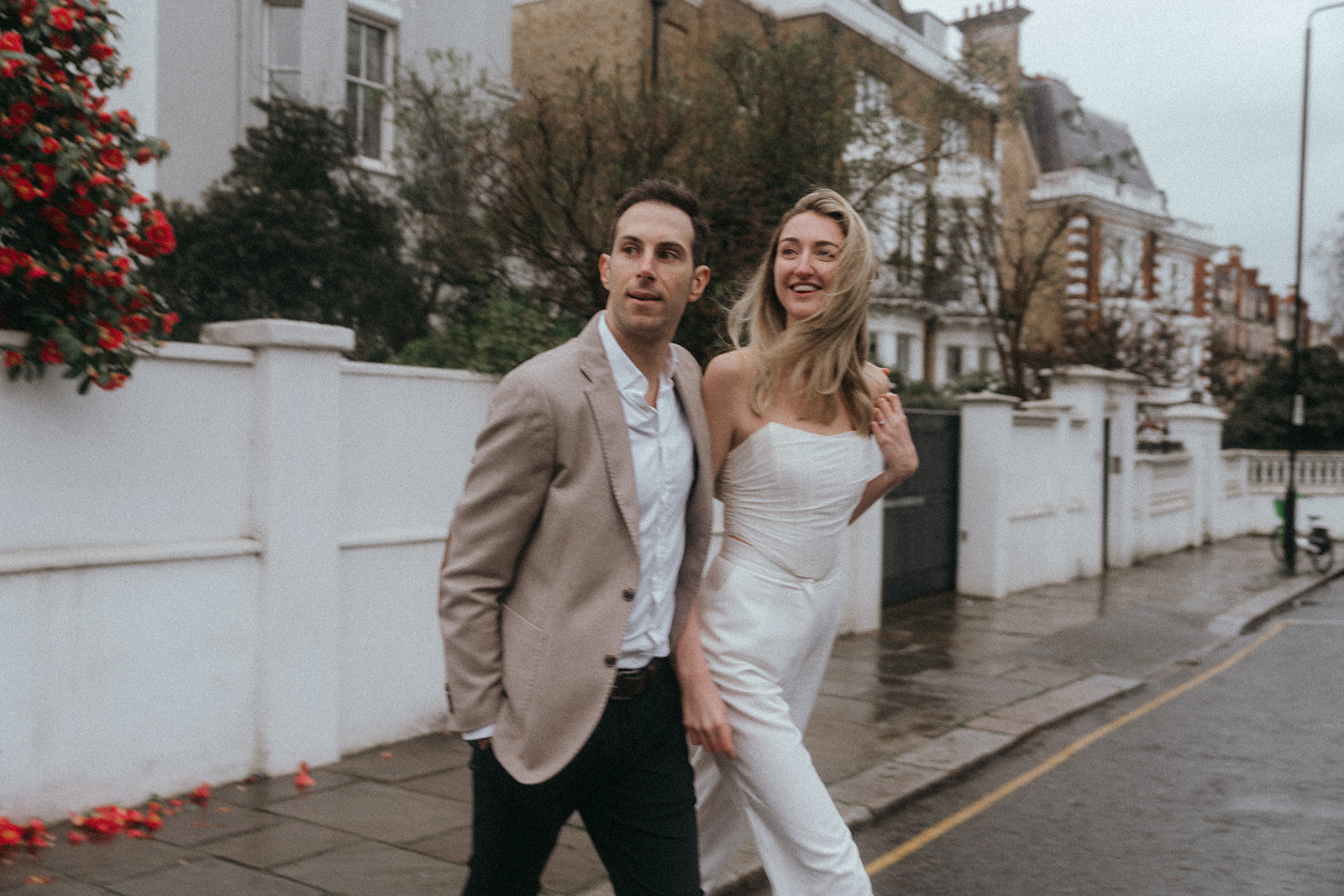 Man and woman looking up a stormy London the street as they cross it, shot by London engagement photographer Elsie Goodman.