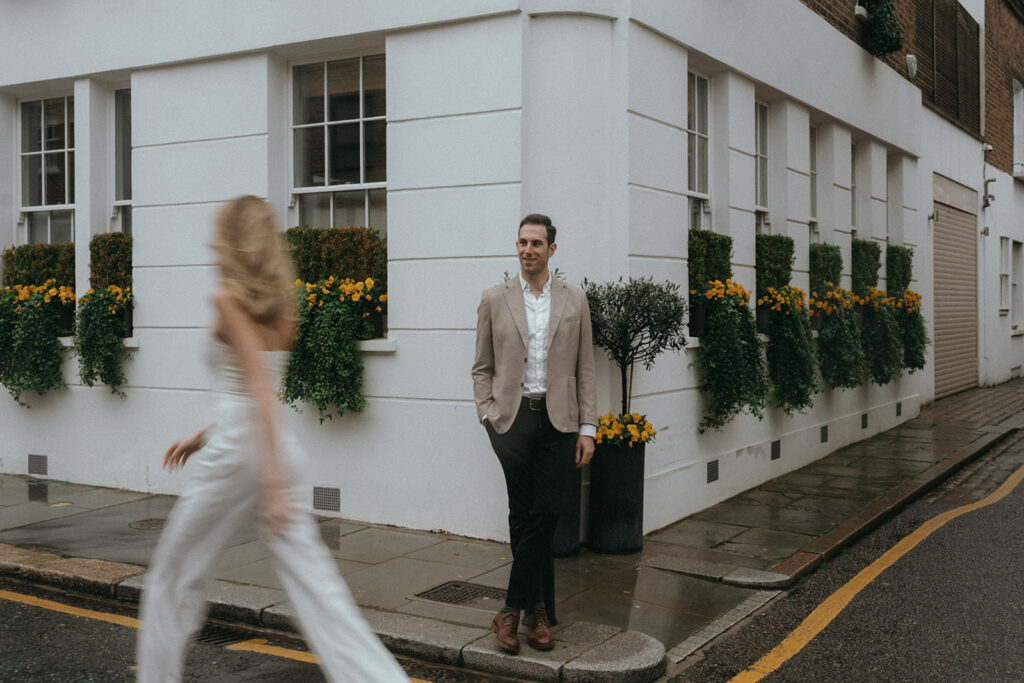 Man standing on a street corner watching a woman walk by, shot by London engagement photographer Elsie Goodman.