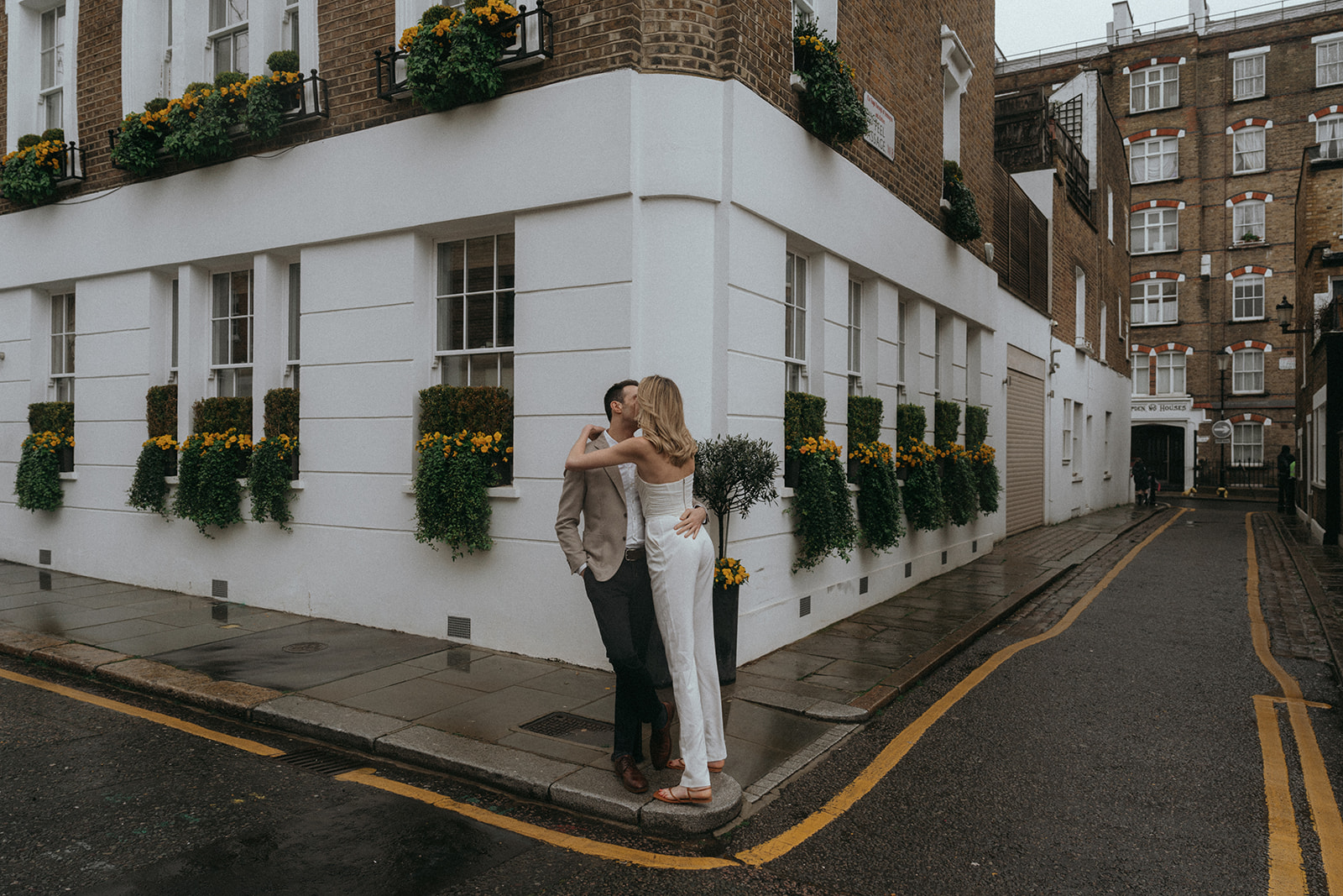 Man and women on a rainy London street corner, kissing, shot by London engagement photographer Elsie Goodman.