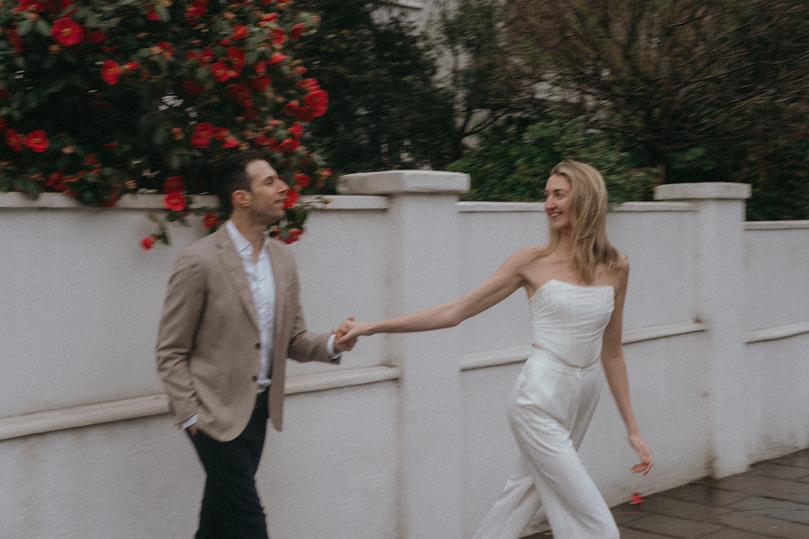 A man and a woman holding hands. The woman's arm is outstretched as she takes a step away, they are in love, shot by London engagement photographer Elsie Goodman.