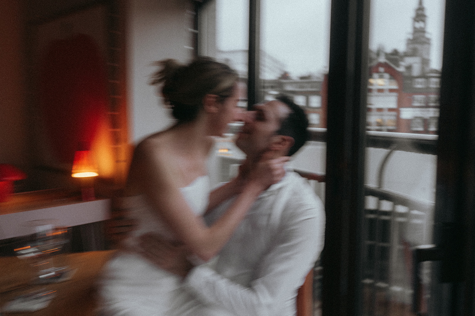 Blurry action shot of a woman sitting on a man's lap about to kiss in their London apartment, shot by London engagement photographer Elsie Goodman.