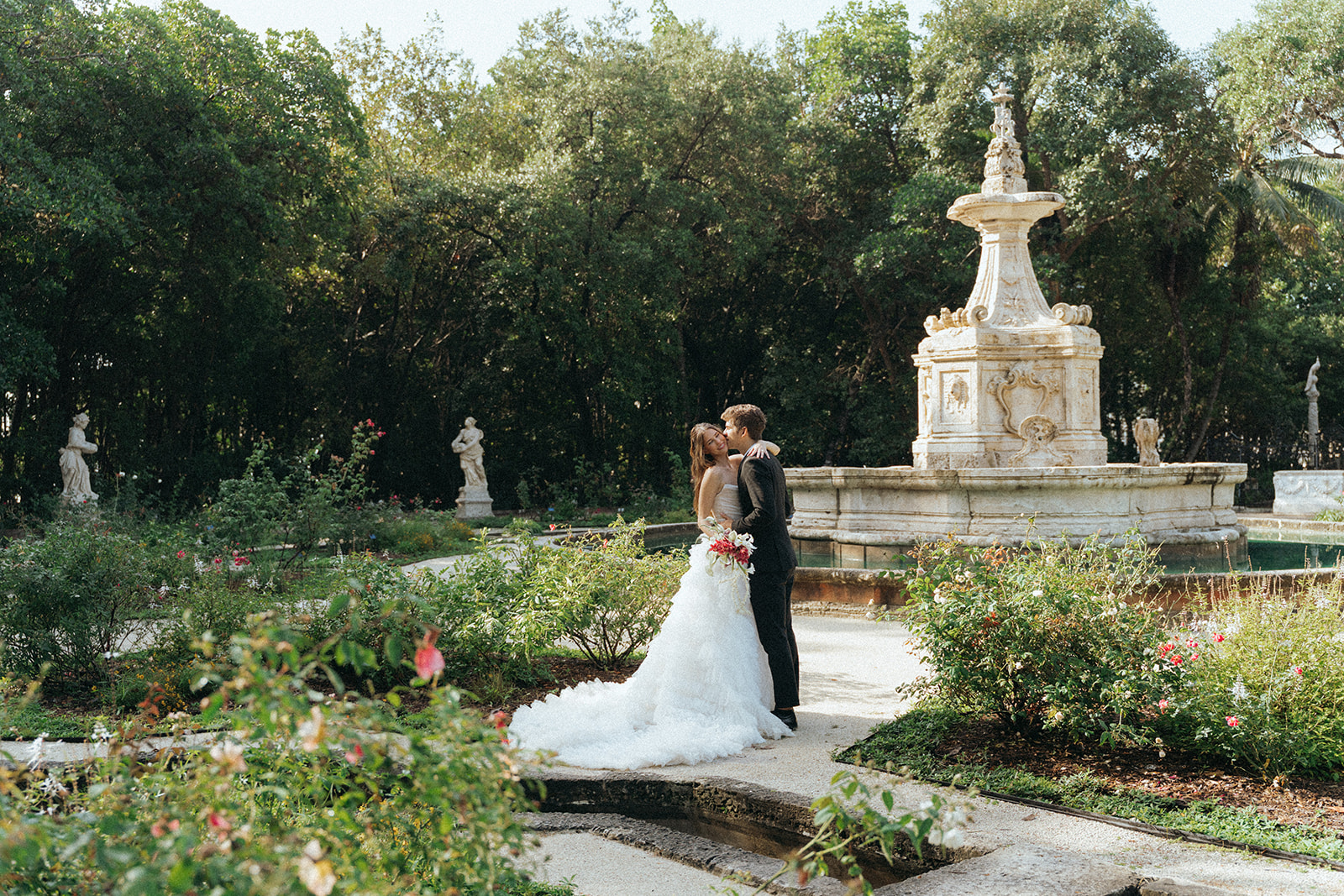 Viscaya Groom kisses bride on the cheek in a beautiful outdoor garden by Vizcaya Wedding Photographer Elsie Goodman.