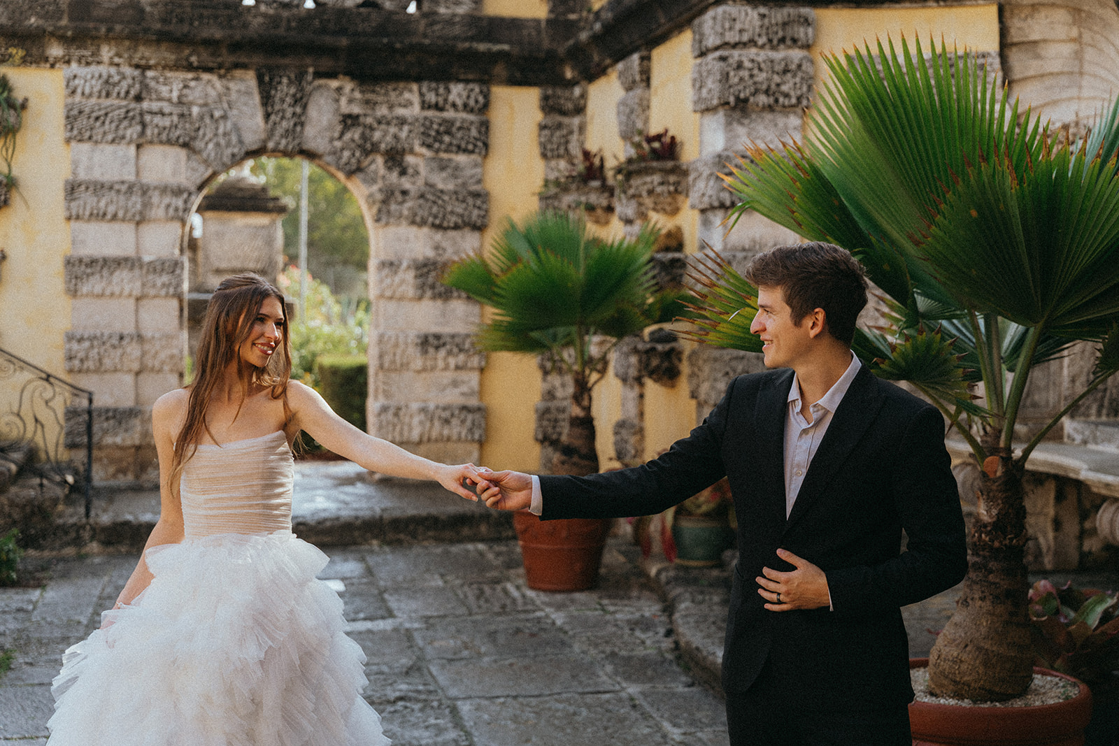 Viscaya Bride with her arm outstretched, her groom takes her hand by Vizcaya Wedding Photographer Elsie Goodman.