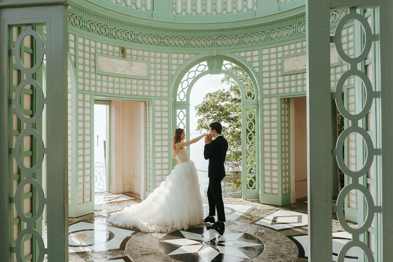 Viscaya groom kissing the hand of his bride in the gazebo by Vizcaya Wedding Photographer Elsie Goodman.
