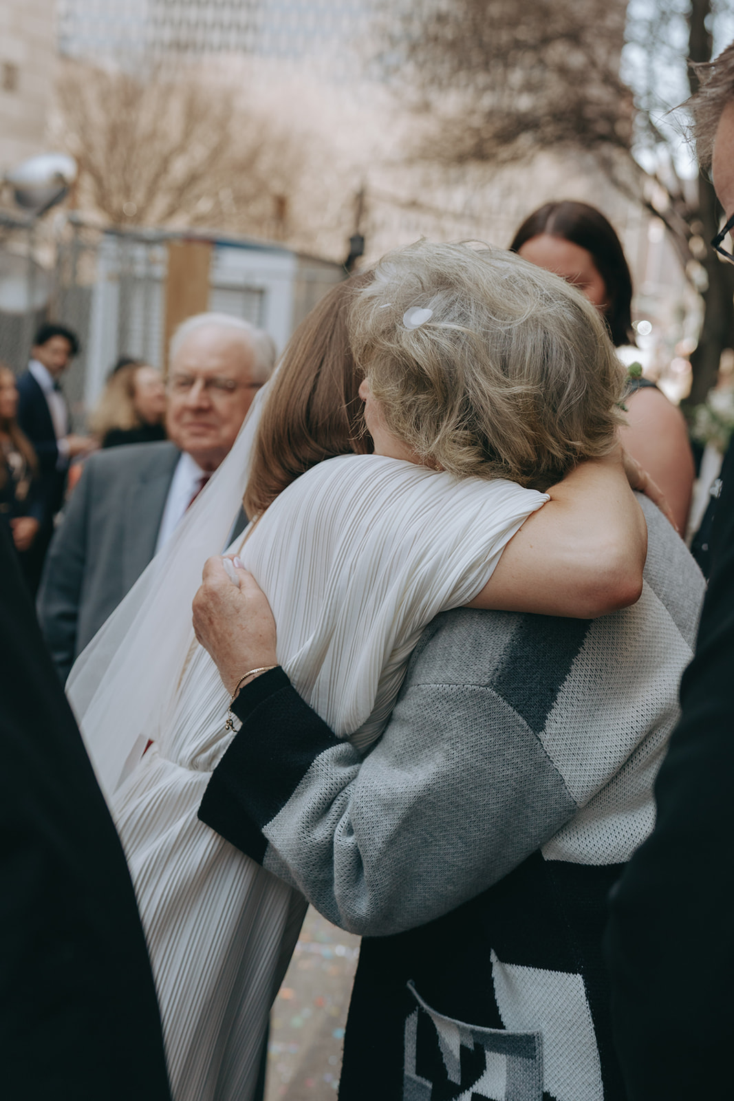 Rachel and Dave’s 2 day celebration Bride hugs her grandmother outside of city hall by NYC city hall wedding photographer Elsie Goodman.