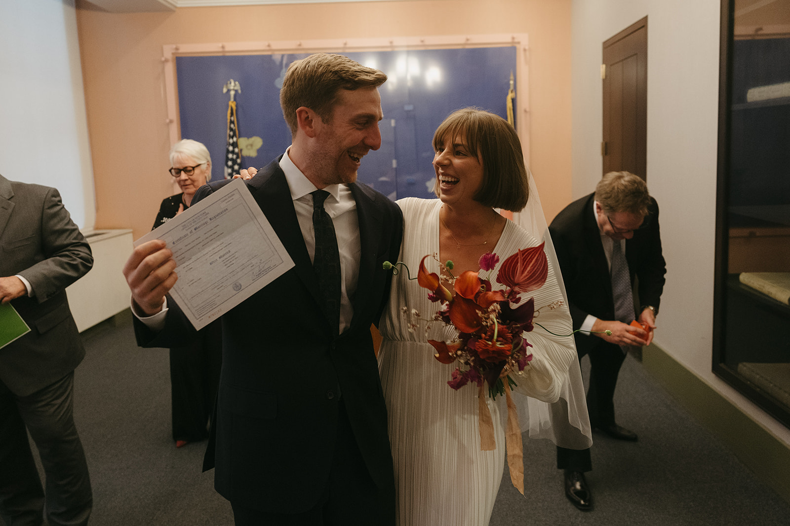 Rachel and Dave’s 2 day celebration Bride and groom looking at each other smiling showing off their marriage certificate by NYC city hall wedding photographer Elsie Goodman.