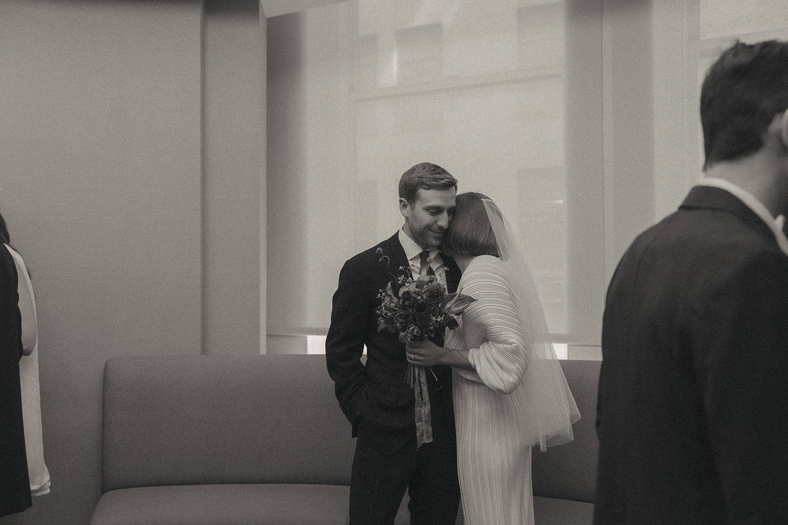 Rachel and Dave’s 2 day celebration Black and white photo of a Bride leaning into a groom, with her face in his neck, holding her bouquet by NYC city hall wedding photographer Elsie Goodman.
