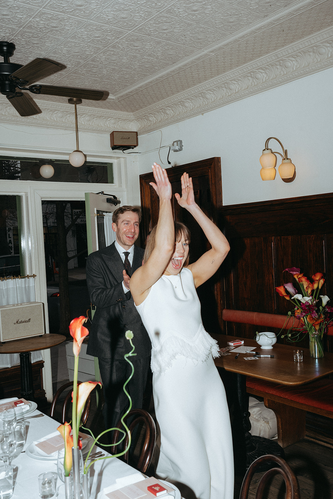 Rachel and Dave’s 2 day celebration Bride and groom walking into their dinner clapping and smiling signs her guest book, which is a deck of cards at Franks restaurant in NYC by NYC elopement photographer Elsie Goodman.