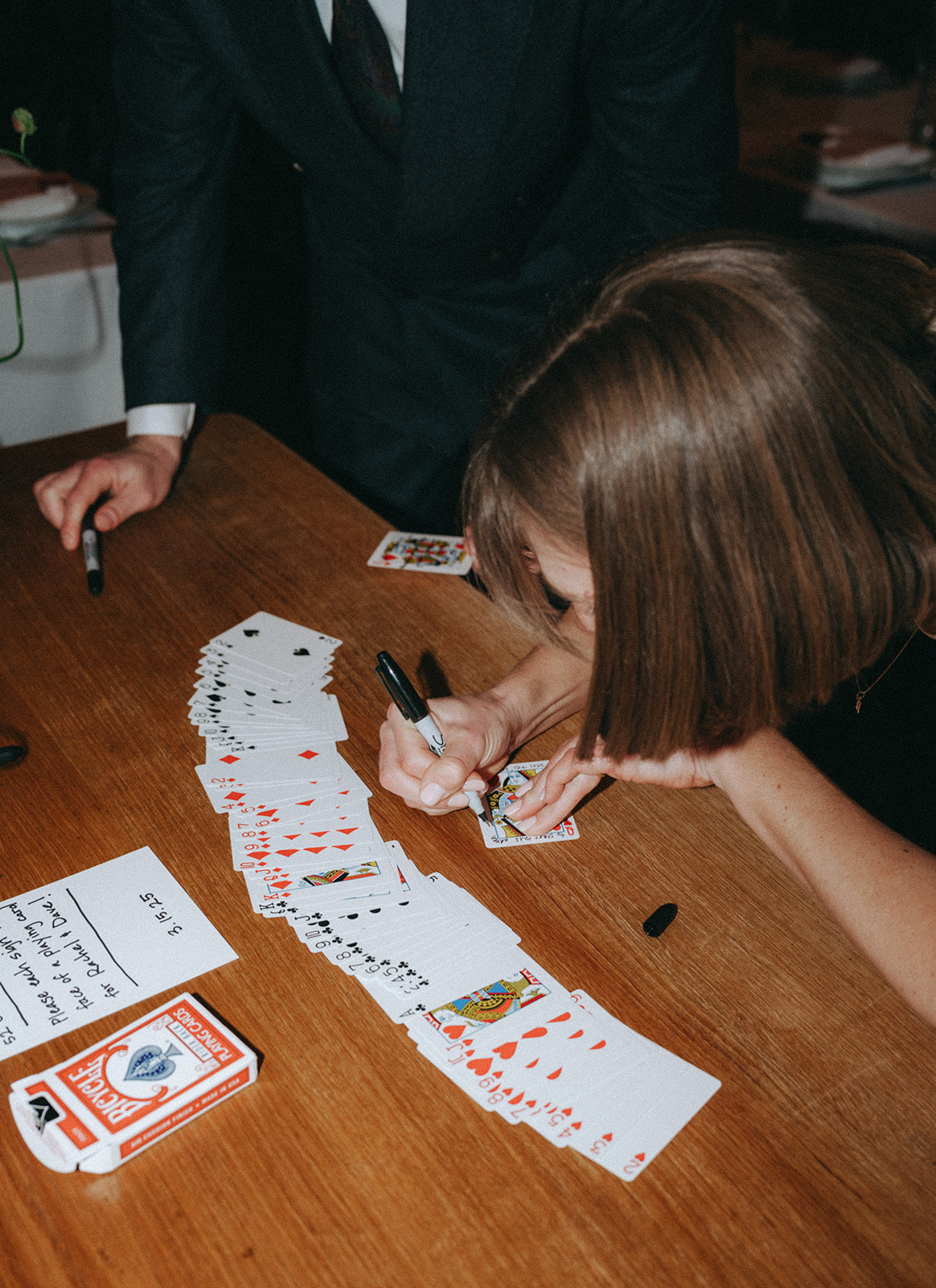 Rachel and Dave’s 2 day celebration Bride signs her guest book, which is a deck of cards at Franks restaurant in NYC by NYC elopement photographer Elsie Goodman.