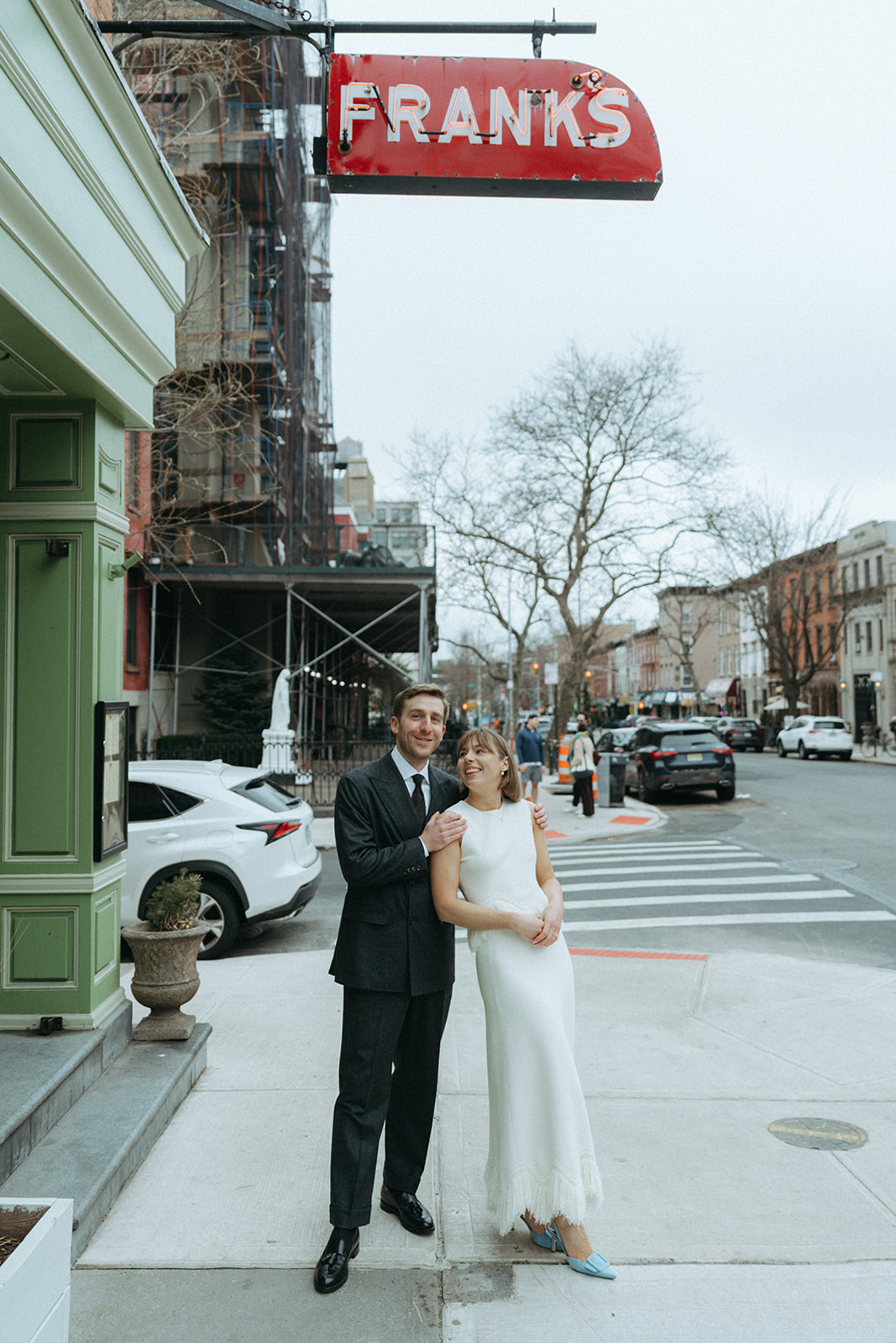Rachel and Dave’s 2 day celebration Bride and groom stand on the street under the red neon sign for Franks restaurant by NYC elopement photographer Elsie Goodman.