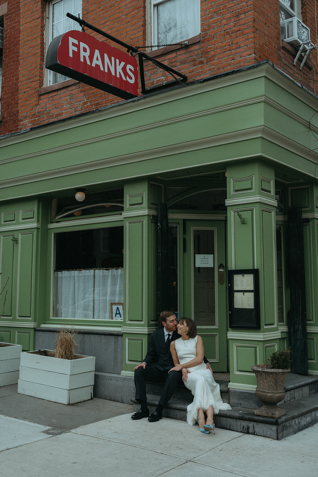 Rachel and Dave’s 2 day celebration Bride and groom sit out front of Franks in NYC by NYC elopement photographer Elsie Goodman.