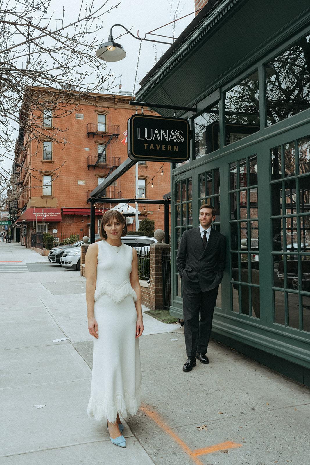 Rachel and Dave’s 2 day celebration Groom stands behind the bride looking at her, she is wearing a white vintage wedding dress by NYC elopement photographer Elsie Goodman.