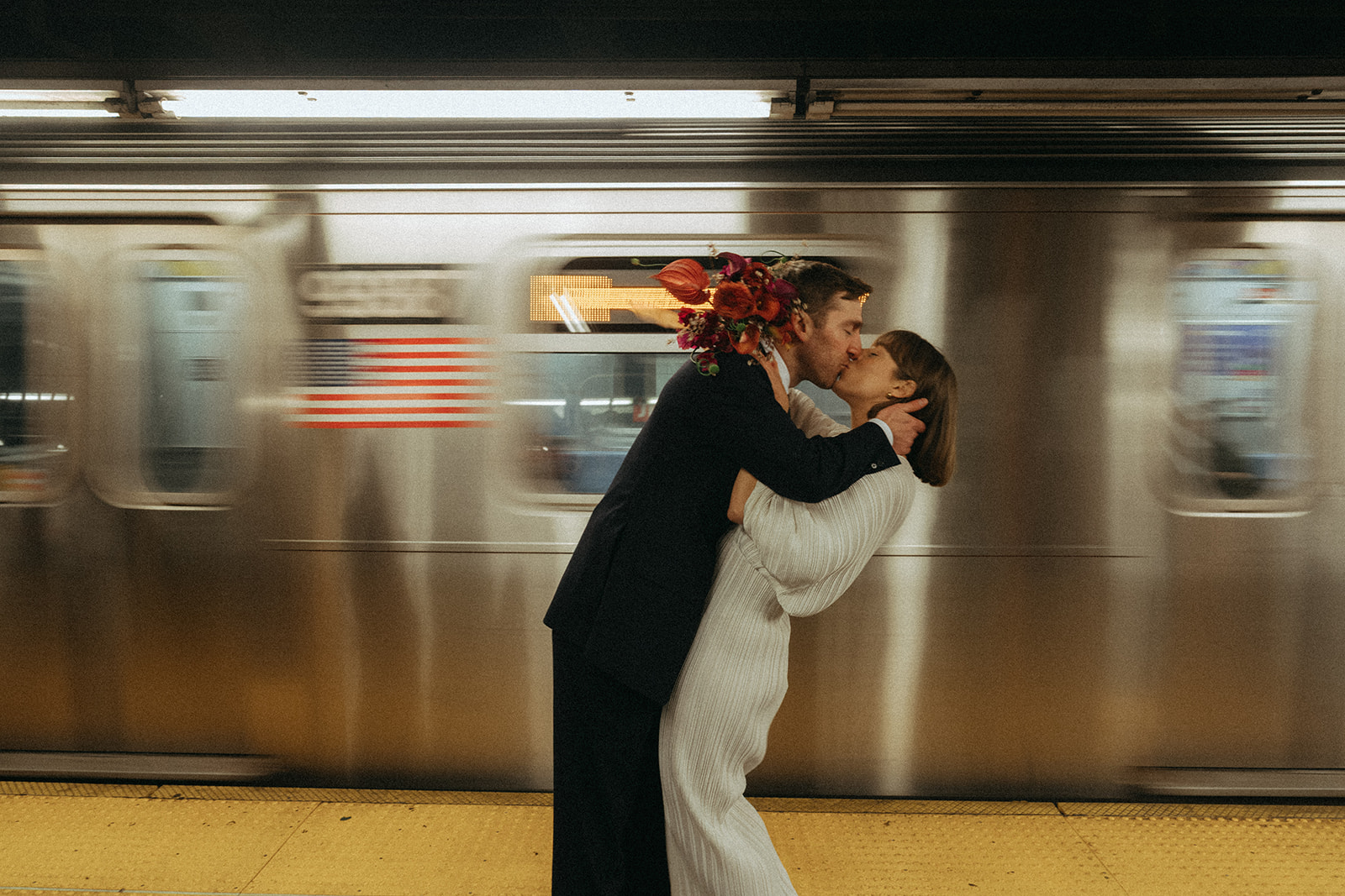 Rachel and Dave’s 2 day celebration bride and groom kissing in front of a moving subway car by NYC city hall wedding photographer Elsie Goodman.