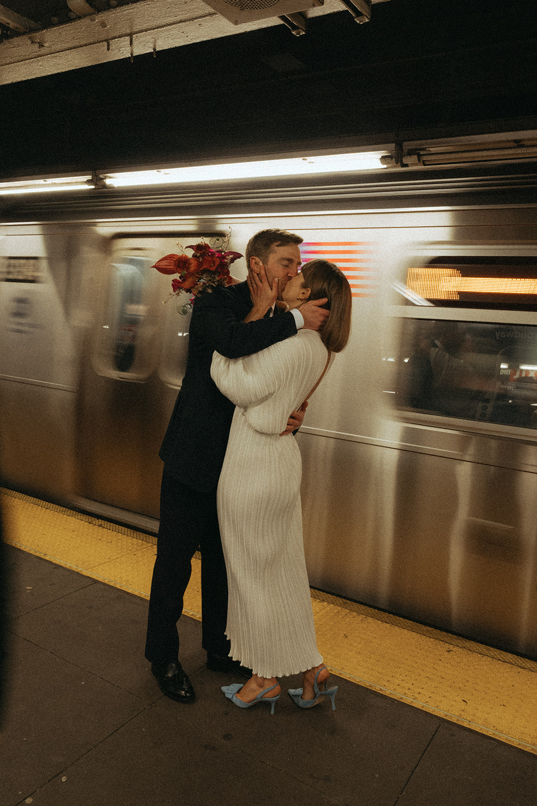 Rachel and Dave’s 2 day celebration Bride and groom kissing in front of a moving subway train by NYC city hall wedding photographer Elsie Goodman.