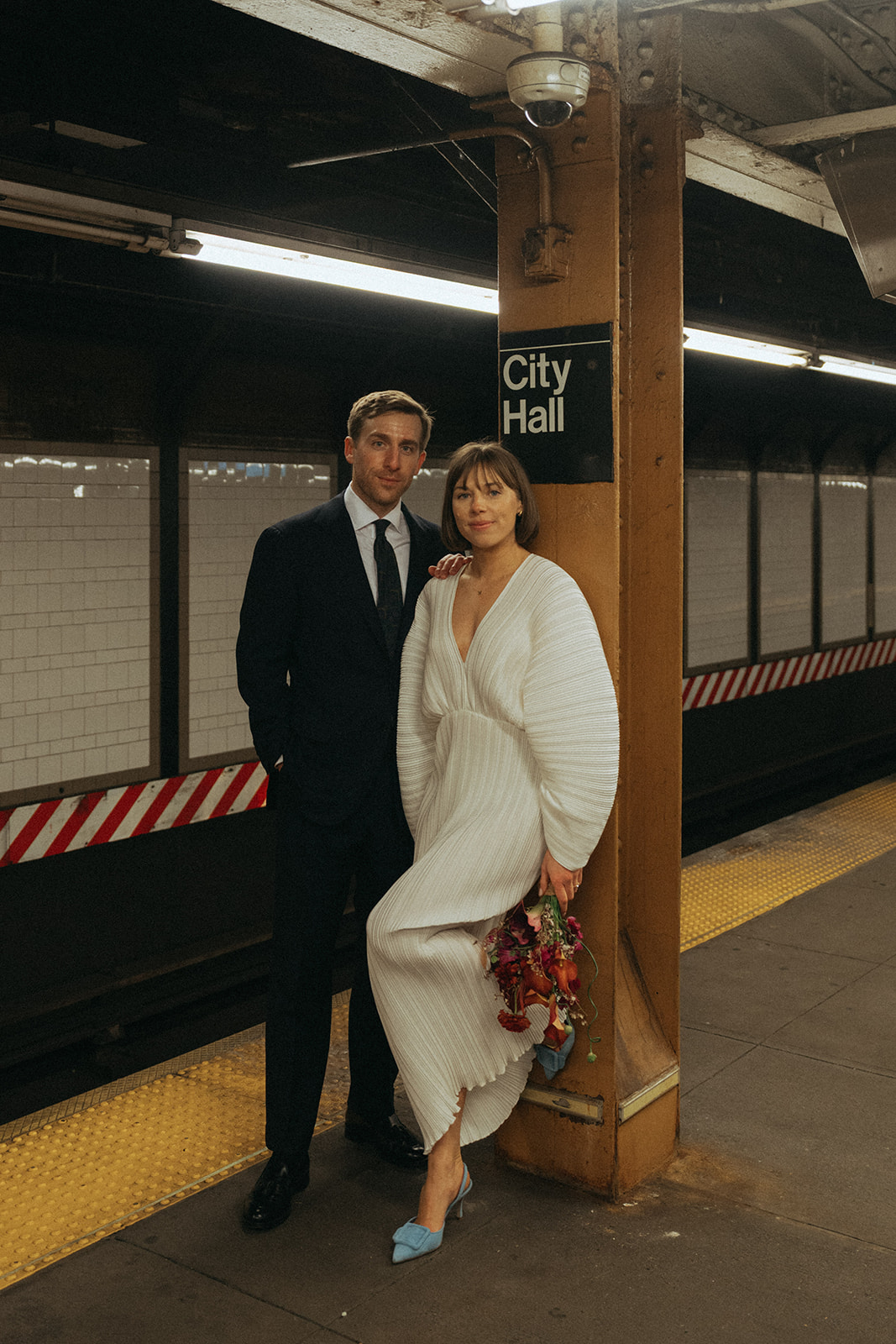 Rachel and Dave’s 2 day celebration Bride and groom leaning against the subway sign for city hall by NYC city hall wedding photographer Elsie Goodman.