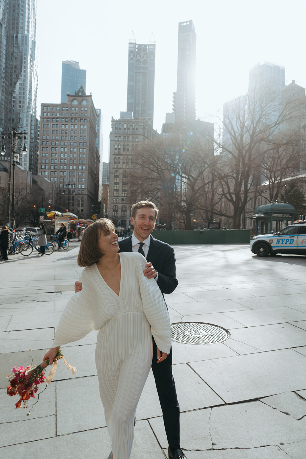 Rachel and Dave’s 2 day celebration Groom stands behind the bride with his hands on her shoulders, bride is laughing by NYC city hall wedding photographer Elsie Goodman.