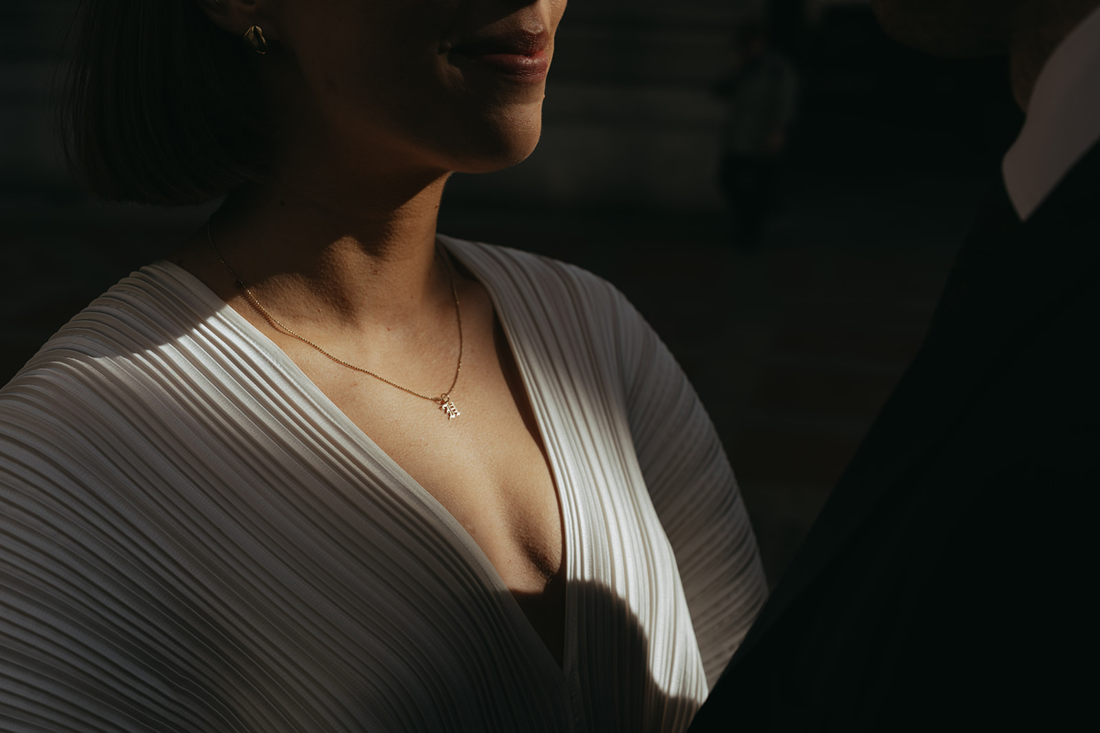 Rachel and Dave’s 2 day celebration Close up of the bride in her vintage wedding dress, a beam of light falling across her lower face and chest, by NYC city hall wedding photographer Elsie Goodman.