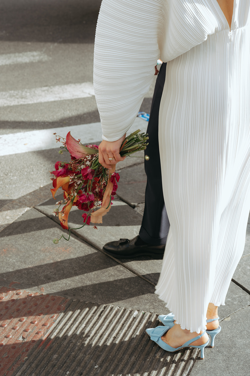 Rachel and Dave’s 2 day celebration Close up of a bride holding her bouquet on a city corner by NYC city hall wedding photographer Elsie Goodman.