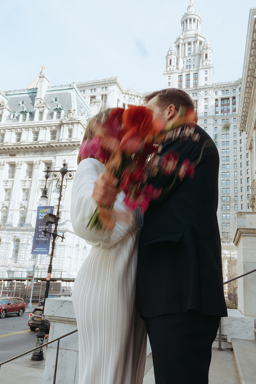 Rachel and Dave’s 2 day celebration Action shot of the bride and groom kissing as she holds her bouquet in front of the camera by NYC city hall wedding photographer Elsie Goodman.