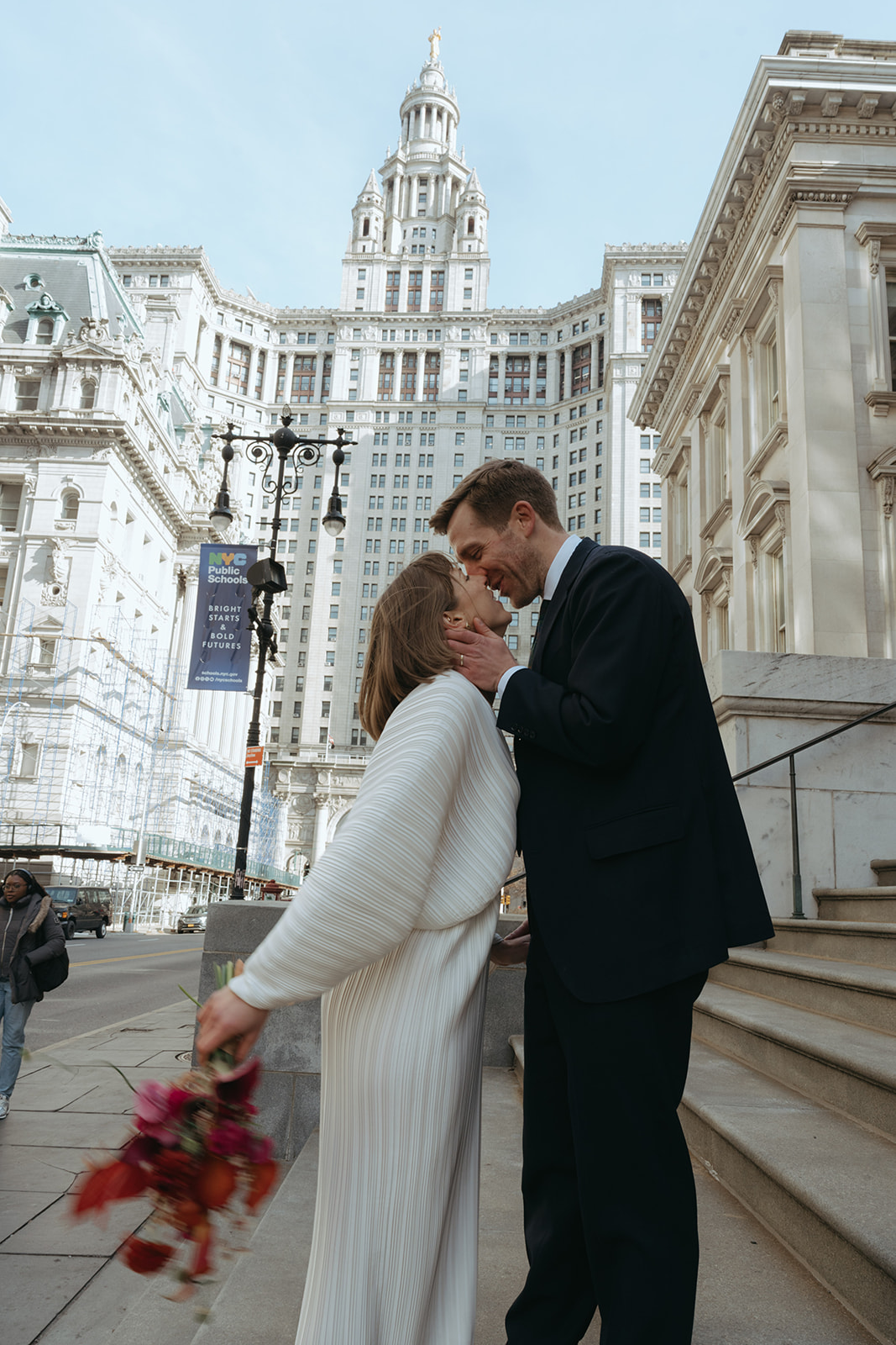 Rachel and Dave’s 2 day celebration Bride and groom lean in for a kiss at the steps of city hall, she holds her colorful bouquet behind her by NYC city hall wedding photographer Elsie Goodman.