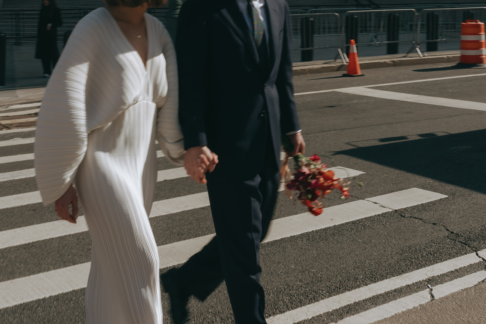 Rachel and Dave’s 2 day celebration Action shot of a bride and groom walking across the street by NYC city hall wedding photographer Elsie Goodman.