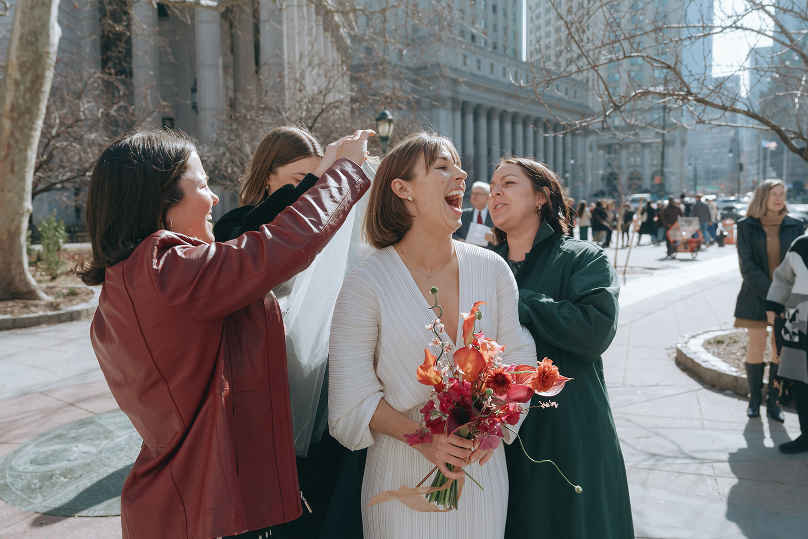 Rachel and Dave’s 2 day celebration Brude in a white vintage wedding dress, laughing as he friends put on her veil by NYC city hall wedding photographer Elsie Goodman.
